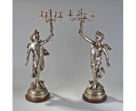 Large pair of putto candelabra, each holding a five branch stick, raised on oak bases, 80cm high