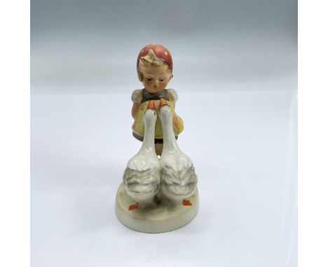 Hand painted figure of a in a yellow and brown dress, red head scarf, looking down at two geese who are resting their heads o
