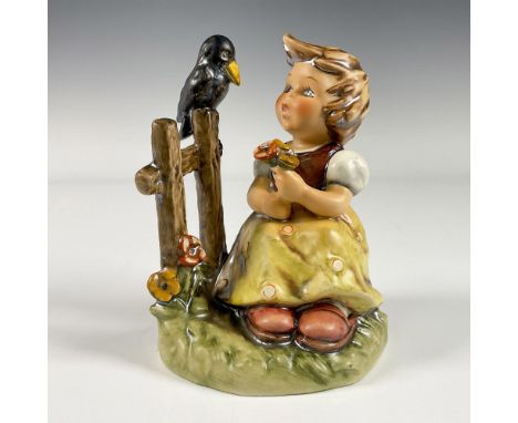 A matte hand painted figure of a young girl holding a bouquet of flowers while she talks to a bird perched on a fence. Goebel