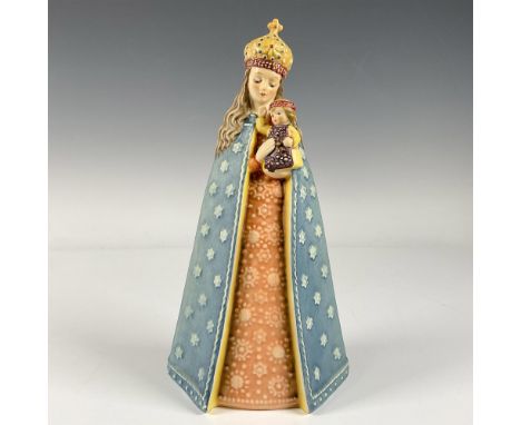 A matte hand painted porcelain figure depicting Madonna holding a child, dressed in a long blue cape adorned with stars. In c