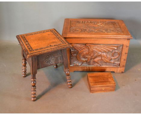 A Carved Oak Blanket Box with four carved panels depicting mythical creatures together with a carved stool on bobbin supports