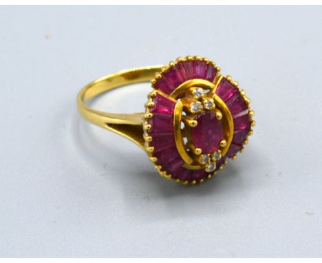 An 18ct Gold Ruby And Diamond Ring set with a central oval ruby flanked by six diamonds and within baguette ruby surround, 5.