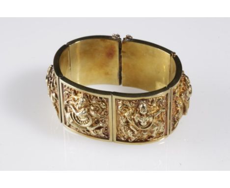 INDIAN YELLOW METAL BANGLE, six conjoined links embossed with a Buddhist deity, with concealed clasp and safety chain, approx