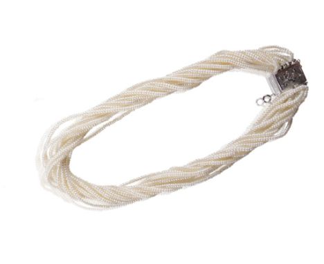 MULTI STRAND SEED PEARL NECKLACE, twelve strands terminating into a white gold engraved clasp, with safety chain, in a leathe