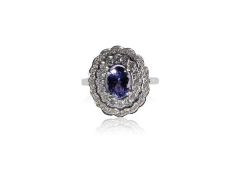 TANZANITE AND DIAMOND CLUSTER RING, the oval-cut tanzanite surrounded by a double border of round-cut diamonds, on a 18k whit