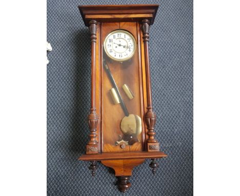 A walnut regulator wall clock with turned and fluted columns to side.