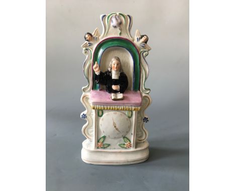 A John Wesley Staffordshire flatback figure preaching from pulpit above clock.