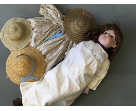 A porcelain faced doll with composite hands, three hats and an extra dress.