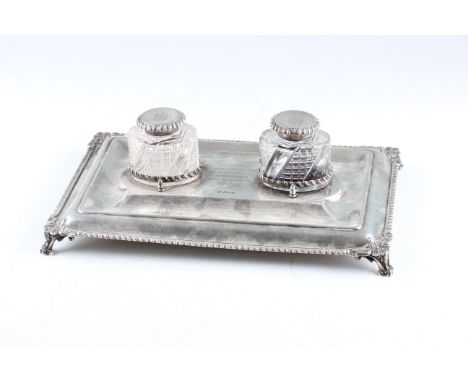 An early 20th Century silver inkwell stand with two inkwells, the stand of rectangular form and raised on four scroll feet, e