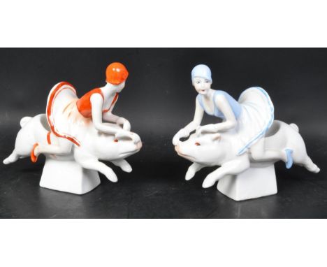 A pair of 20th century Art Deco style ceramic bookends in the shape of two ladies riding pigs. One in light blue colourway, o