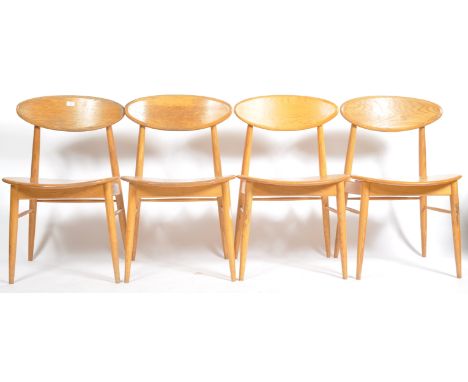 A set of four retro contemporary 21st Century elm / oak dining chairs in the manner of Ercol an oval panel back with panel se