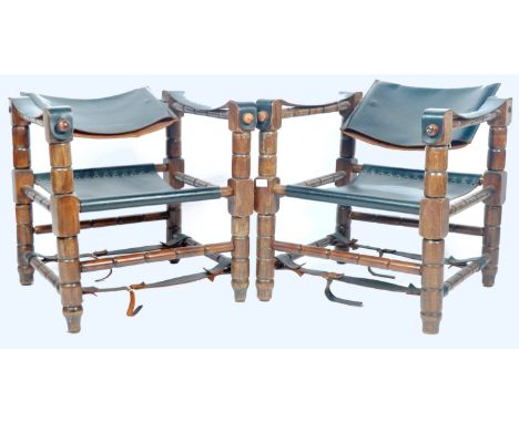 A matching pair of retro vintage 20th Century Safari Chairs / armchairs of teak wood construction having black leather uphols