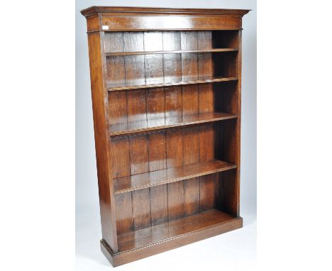 An antique 20th Century tall oak bookcase / display shelves of upright slender form having flared cornice top with a series o