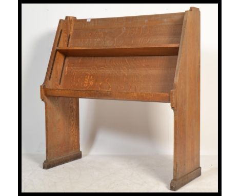 An early 20th Century ecclesiastical Arts and Crafts style open library bookcase trough - shop display stand beingfitted with