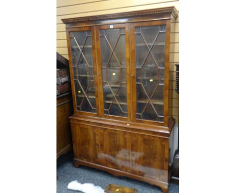 A REPRODUCTION LIGHT MAHOGANY CUPBOARD BOOKCASE, three astragal glazed upper doors above a three cupboard base