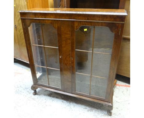 VINTAGE WALNUT TWO-DOOR DISPLAY CABINET on raised feet, with carved decoration to the top