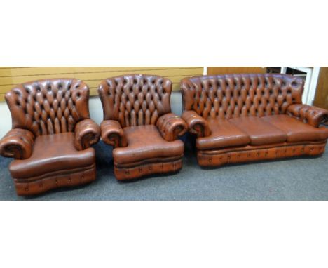BROWN LEATHER THREE-PIECE SUITE comprising three seater sofa with studded back and two matching arm chairs