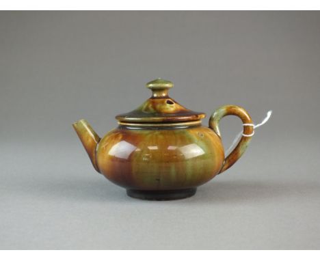 A Dunmore pottery toy teapot and cover circa 1870 of compressed globular form decorated in a brown and green trailed glaze, i