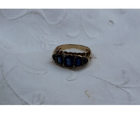 A sapphire and diamond line ring with graduated faceted oval sapphires and diamond chips to a 9ct yellow gold setting and sha