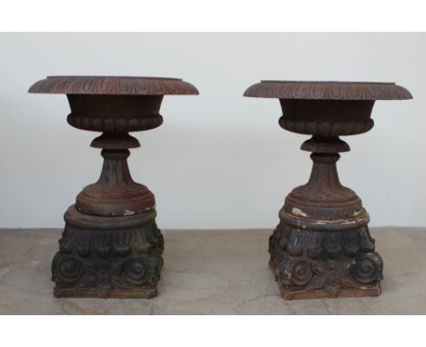 A pair of impressive cast iron urn planters with a flared gadrooned rim, spreading foot and separate leaf cast base, 65cm dia