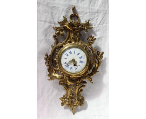 An ormolu wall clock, of rococo form decorated with scrolls and leaves, the circular enamel dial with blue Roman numerals, 63