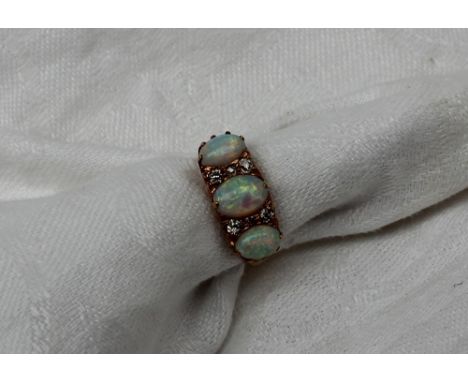 An opal and diamond dress ring, set with three oval opals and six old cut diamonds to a yellow metal setting and shank