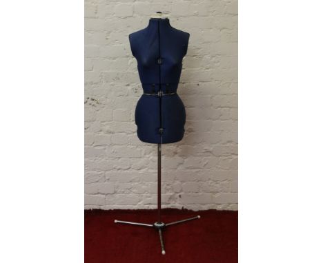 An adjustable dressmakers manekin raised on a chrome tripod stand.