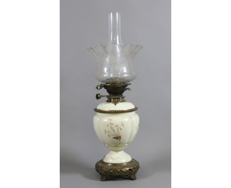 A Victorian oil lamp with brass and opaque glass base decorated with flowers along with an etched glass shade and chimney.