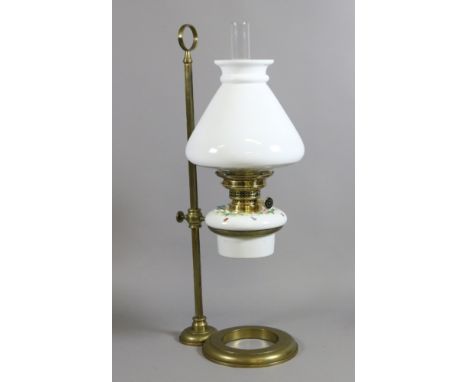 A Victorian brass rise and fall oil lamp with continental ceramic font moulded with flowers and opaque glass shade and chimne