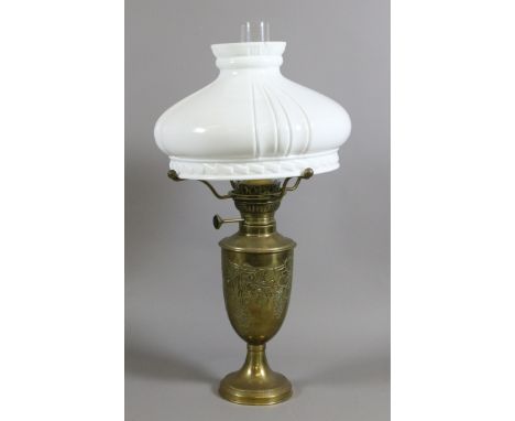 An ornate brass based oil lamp with opaque glass shade and chimney.