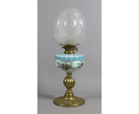 An Art Nouveau brass based oil lamp with opaque painted glass font and etched glass shade decorated with flowers.