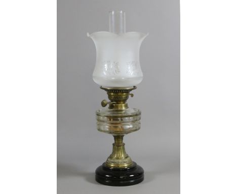 A Victorian brass based oil lamp with faceted clear glass font, etched glass shade and chimney.