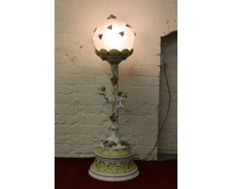 A Capodimonte floor standing ceramic light decorated with cherubs and flowers with translucent shade.