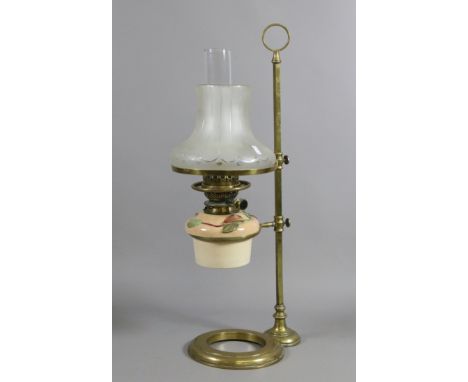 A Victorian brass based rise and fall oil lamp with ceramic font moulded with leaves and etched glass shade.