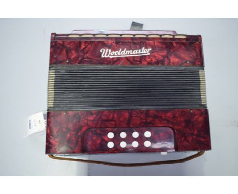 A Worldmaster small accordion, in red plastic case.