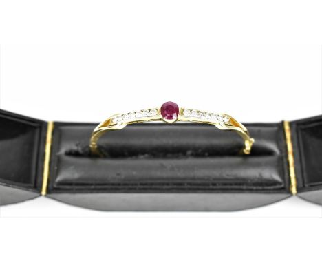 An 18ct yellow gold, ruby and and diamond bangle, with central cut ruby flanked by a row of seven brilliant cut diamonds eith