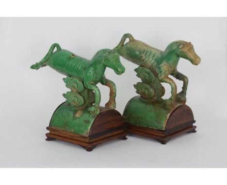 A pair of Chinese glazed pottery roof tiles, 17th Century        Each modeled as a horse leaping over a cloud scroll, on an a