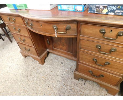 MAHOGANY FRAMED BOW FRONTED LEATHER TOPPED DESK WITH NINE DRAWERS AND ONE CUPBOARD DOOR WITH RED LEATHER INSERT 