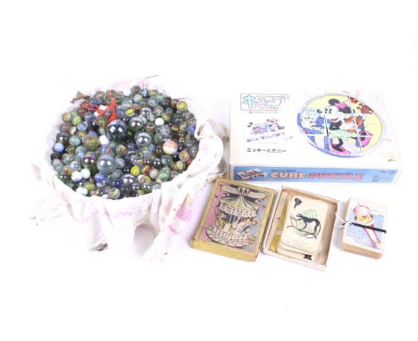 An assortment of vintage games. Including glass marbles, a Japanese Disney jigsaw, packs of cards and more