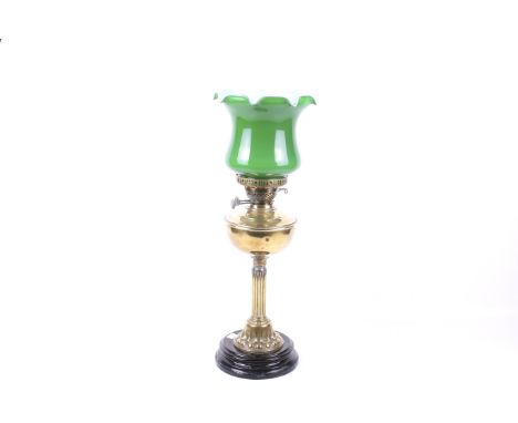 A Victorian brass oil lamp. Having a clear glass funnel and green glass shade with a ribbed edge, the Corinthian column stand