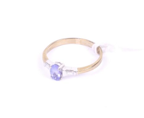 A modern 9ct white and yellow gold, tanzanite and diamond three stone ring. The central oval mixed-cut pale-blue tanzanite, b