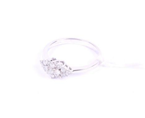 A modern 9ct white gold and diamond floral cluster ring. The central raised four stone cruciforn section between diamond tref