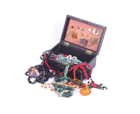 An assortment of costume jewellery. Including a jet necklace, orange beads, ceramic brooches, filigree pendants and more, con