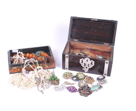 An assortment of costume jewellery. Including a jade brooch, orange beads, ceramic and enamel brooches, imitation pearl neckl