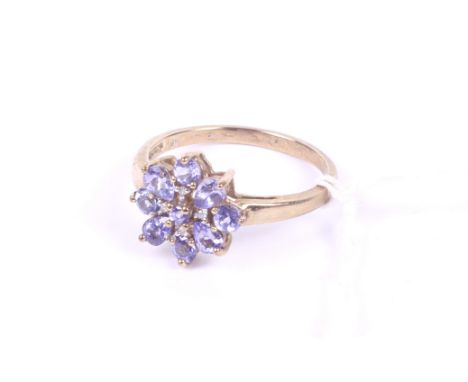 A modern 9ct gold, tanzanite and diamond flower-head cluster ring. The nine pear-shaped and round tanzanites with four small 