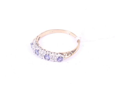 A vintage gold, tanzanite and diamond five stone ring. The four small round tanzanites with tiny illusion-set diamond spacers