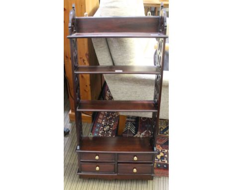 A REPRODUCTION MAHOGANY FINISHED SET OF HANGING SHELVES with pierced plank side supports, having a bank of four drawers below