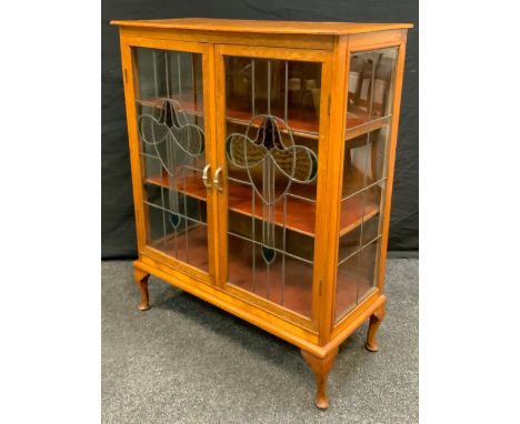 An Arts &amp; Crafts light oak two door display cabinet, stained leaded glass doors, 115cm high, 92cm wide, 41.5cm deep. 