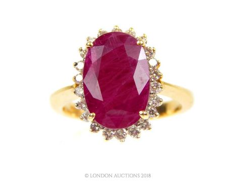 An 18 ct yellow gold, ruby and diamond cluster ring, composed of a central, four-claw set natural, faceted, oval-shaped ruby 