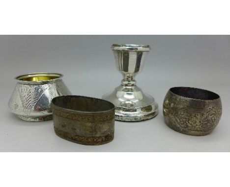 A silver salt, two silver napkin rings, weight 97g, and a small silver candlestick